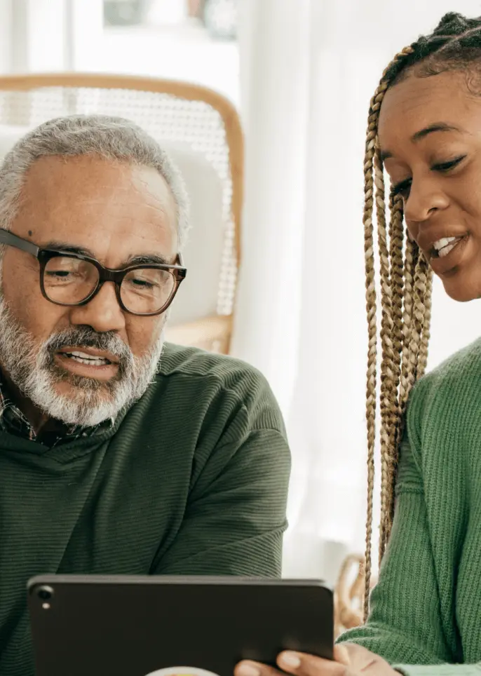 Father and older daughter look at a tablet together.