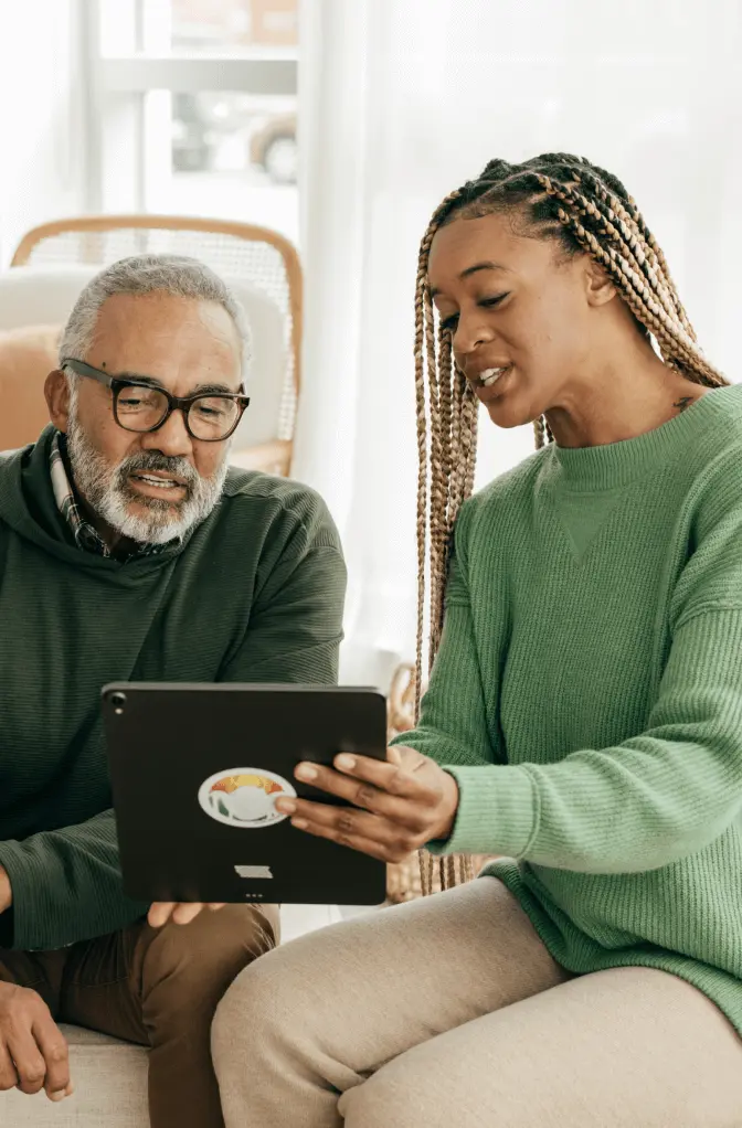 Father and older daughter look at a tablet together.