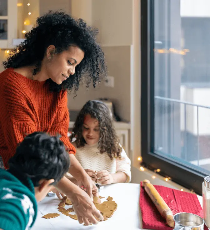 Family bakes cookies in the warmth of their home by a window.