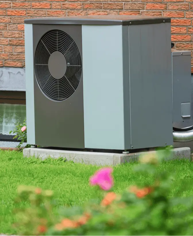 Outdoor heatpump against a brick wall of a house.